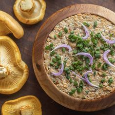 a wooden bowl filled with food next to sliced mushrooms and green onions on a table