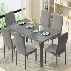 a dining room table with grey chairs and plates on the placemat in front of it