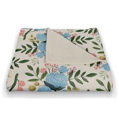 a white blanket with blue flowers and green leaves on the bottom is folded in half