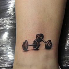 a black and white photo of a dumbbell tattoo on the ankle