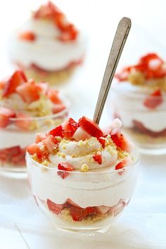 small desserts with strawberries and whipped cream in glass bowls on a white table