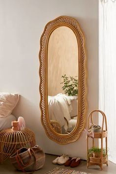 a mirror sitting on top of a wooden floor next to a basket filled with plants