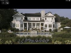 a large white house with a pool in the front yard and lots of flowers around it