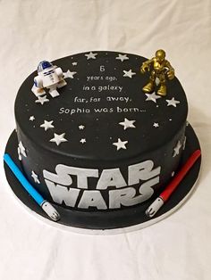 a star wars themed cake on a white tablecloth with two small toy figurines