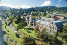 an aerial view of a large building in the middle of trees and buildings with mountains in the background