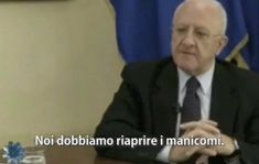 an older man sitting at a table in front of a blue and white flag with the words, not doblama raprie i manicomi