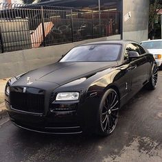 a black rolls royce parked on the side of the road in front of a building