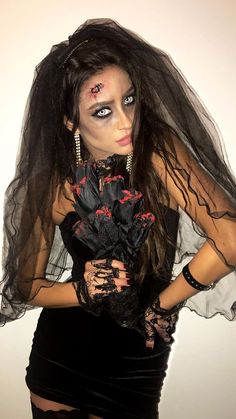 a woman with makeup on her face and black veil over her head is posing for the camera