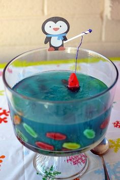 a glass bowl filled with blue liquid and a penguin stick sticking out of the top