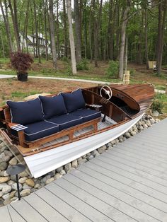 a boat that is sitting on the ground near some rocks and grass with trees in the background