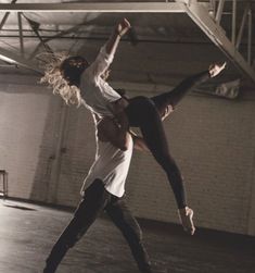 two people are dancing together in an empty room, one is holding the other's leg