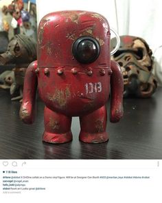 an old red robot toy sitting on top of a table