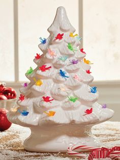 a white ceramic christmas tree sitting on top of a table next to candy canes