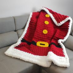 a crocheted santa claus blanket sitting on top of a couch next to a pillow