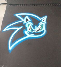 a drawing of a cat's face on a black notebook with blue and green eyes