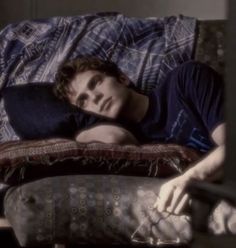 a young man laying on top of a couch next to a pillow in a living room