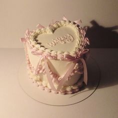 a heart shaped cake sitting on top of a white plate with pink ribbon around it