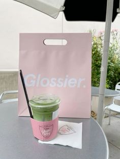 a pink and green drink sitting on top of a table next to a white umbrella