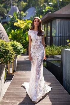 a woman in a white dress standing on a wooden walkway