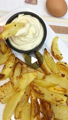 a person dipping some kind of mayonnaise on french fries