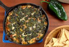 a casserole with spinach and cheese in a blue dish next to some tortilla chips