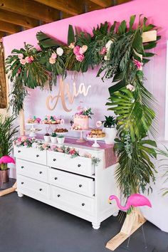 the dessert table is decorated with pink flamingos and greenery for an aloha party