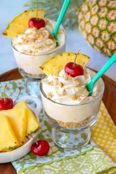 three desserts with pineapple, cherries and whipped cream in small glass bowls