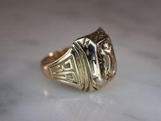 Herff Jones Art Deco style 10k yellow gold ring is size 7. Band tapers from 15mm to 3mm with beveled plaque on top. Plaque design consists of a shield with the name of the school engraved on it, which is too worn to see. Bevels are decorated with geometric patterns and engraved with the letters D and J. The sides of the ring have the numbers 19 and 36 incised into them, all in a high polish finish. Stamped HJ.CO SUPERTONE PATENTED. 14k Gold Art Deco Signet Ring With Polished Finish, Art Deco Gold Signet Ring With Polished Finish, Collectible Art Deco Signet Ring With Polished Finish, Art Deco Engraved Gold Ring, Art Deco Gold Engraved Ring, Herff Jones, Gold Class, Plaque Design, Diamond Engagement Band