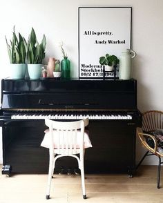 a black piano sitting in the corner of a room next to a chair and potted plants