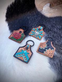 four wooden tags with designs on them sitting on a fur surface next to a black and white rug