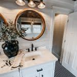 a bathroom with two round mirrors above the sink and a vase on the counter next to it