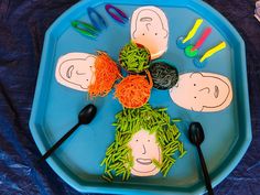 a blue plate topped with cut out faces and vegetables