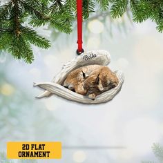 an ornament with a cat curled up in a fish - shaped bed hanging from a christmas tree