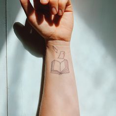 a person with a book tattoo on their arm