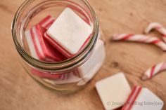 some candy canes are in a jar on a wooden table next to peppermints