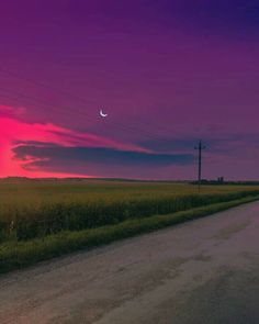 the sun is setting over an empty country road with power lines and telephone poles in the distance