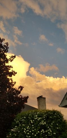 the top of a building with a clock on it's face and clouds in the background