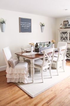 a dining room table with white chairs and flowers