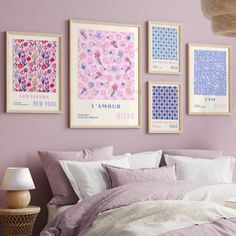 a bedroom with pink walls and pictures on the wall above the bed, along with a wicker basket