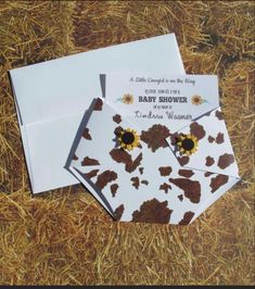 two baby shower cards with sunflowers on them are laying in the hay next to each other