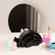 an assortment of makeup products sitting on top of a white table next to a mirror