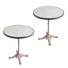 two tables with white marble top and metal base, one is turned upside down to the side