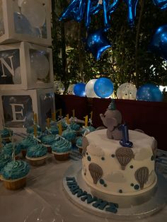 a table topped with cupcakes and cakes covered in blue frosted icing