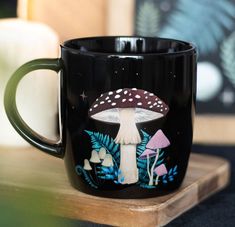 a black coffee mug with mushrooms painted on it