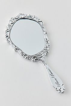 a mirror that is sitting on top of a white surface with the reflection of a spoon in it