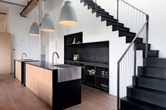 an open kitchen with black cabinets and stairs