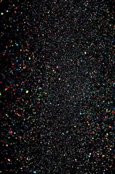 an abstract black background with multicolored confetti sprinkles on it