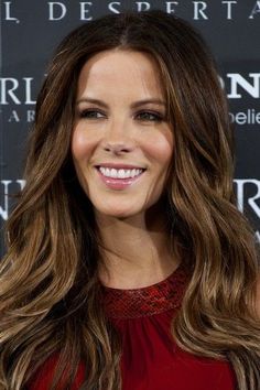 a woman with long brown hair smiling at the camera