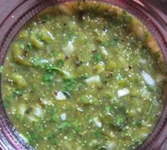 a glass bowl filled with green soup on top of a table