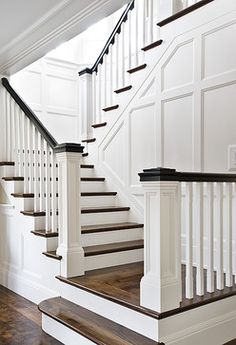 a white staircase with black railing and handrail